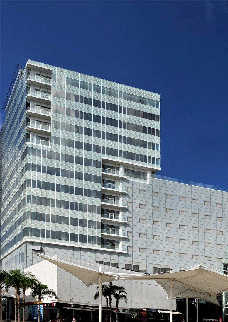 Exterior view of the glass-facade Corporativo Malecon Americas building against a blue sky.