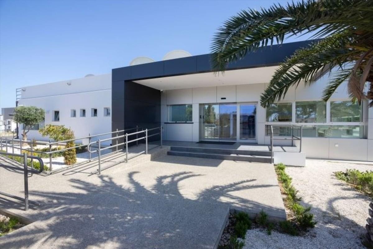 Exterior entrance of the Edificio Mundo Plaza building featuring a modern white facade and palm trees.