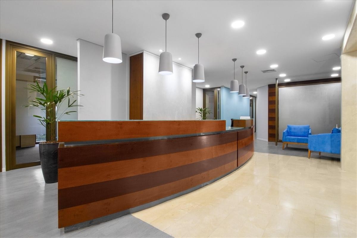 Modern wooden reception desk at Av. Brigadeiro Faria Lima, 3729 with hanging pendant lights.