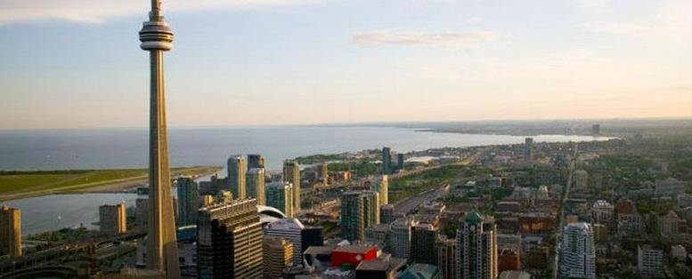 Aerial panoramic view of the Toronto skyline featuring the CN Tower and Lake Ontario.