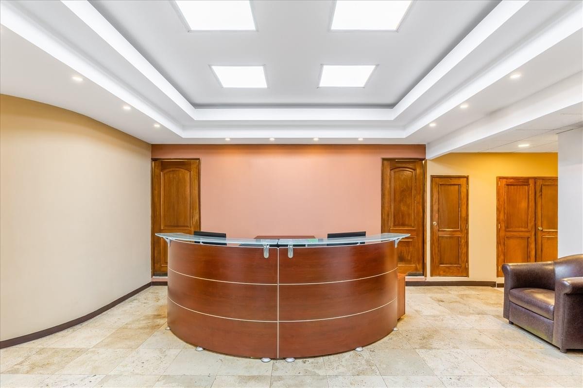 Spacious reception area with a curved dark wood desk and warm lighting.