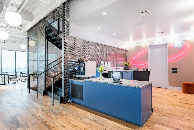 Modern reception area at Houston Galleria, 2700 Post Oak Boulevard with a blue desk and neon wall art.
