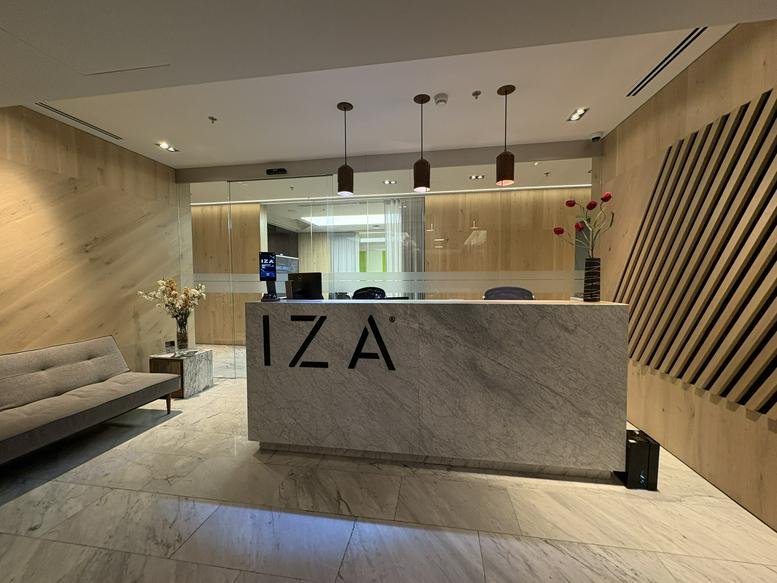 Minimalist marble reception desk with IZA branding and wood slat wall.