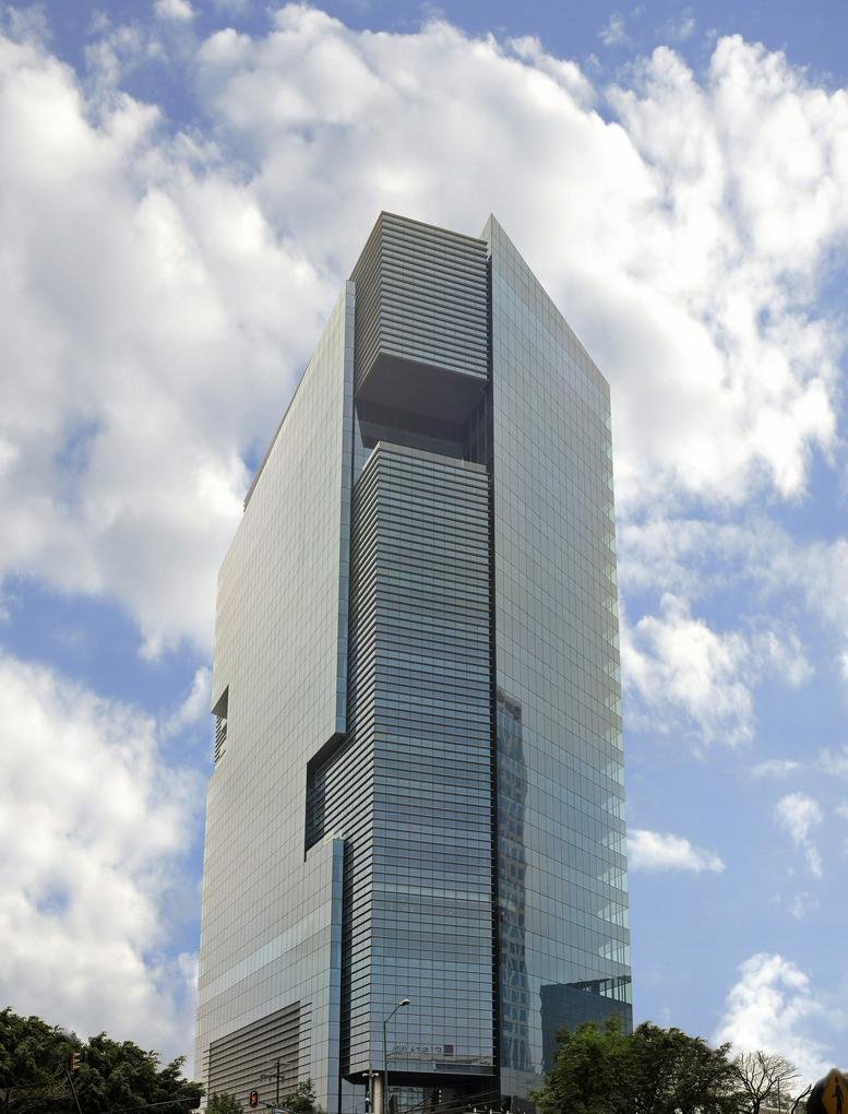 Exterior view of a modern high-rise building with a glass facade and geometric design.