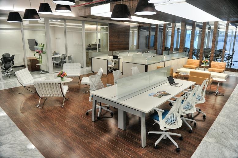 Bright coworking lounge with wooden floors, white designer chairs, and modern pendant lighting.