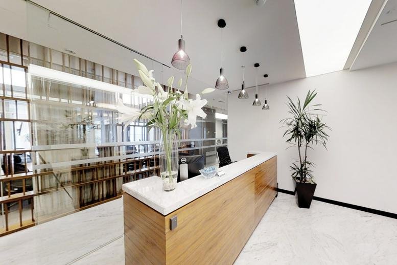 Bright reception desk with warm wood paneling, white marble floors, and fresh lilies.