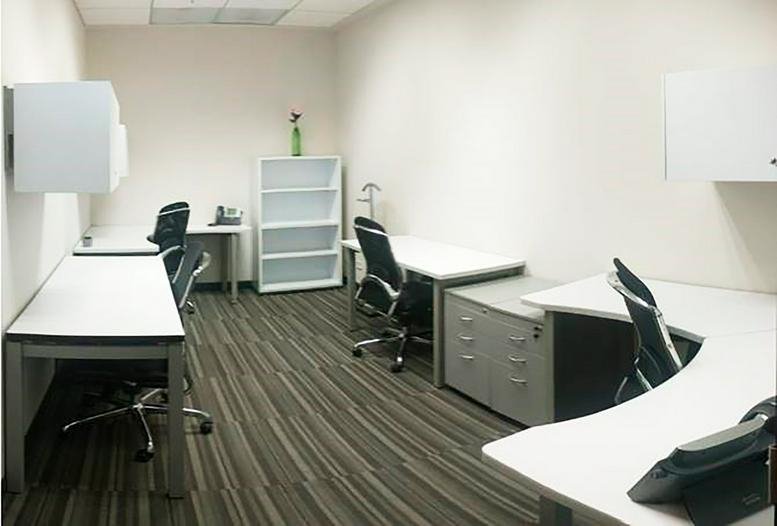 Quiet internal office room with several white desks and a tall white bookshelf.