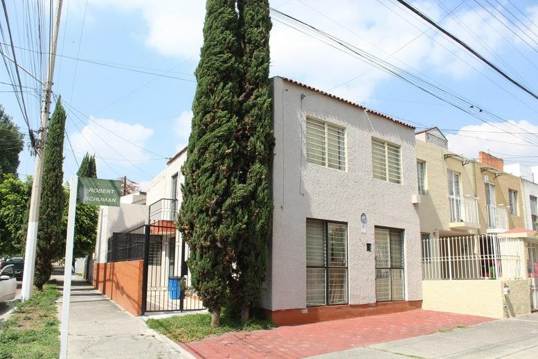 Exterior view of the Providencia Business Center, Zapopan featuring a white facade and tall cypress trees.