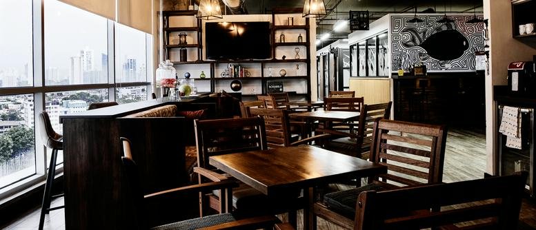 Kenex Plaza lounge with wooden tables, shelving, and large windows.