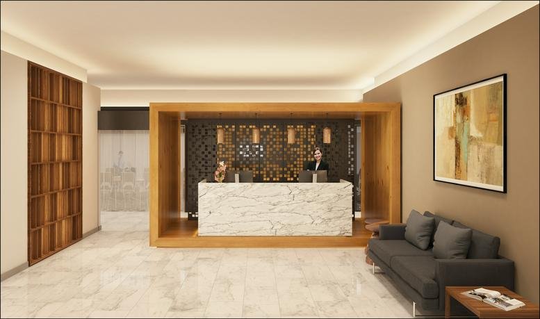 Bright reception area featuring a marble desk and a comfortable grey sofa.