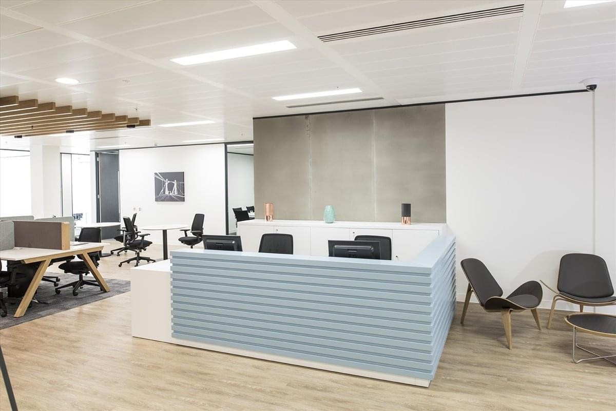 Reception area at Las Artes Building featuring a light blue corrugated front desk and wooden flooring.