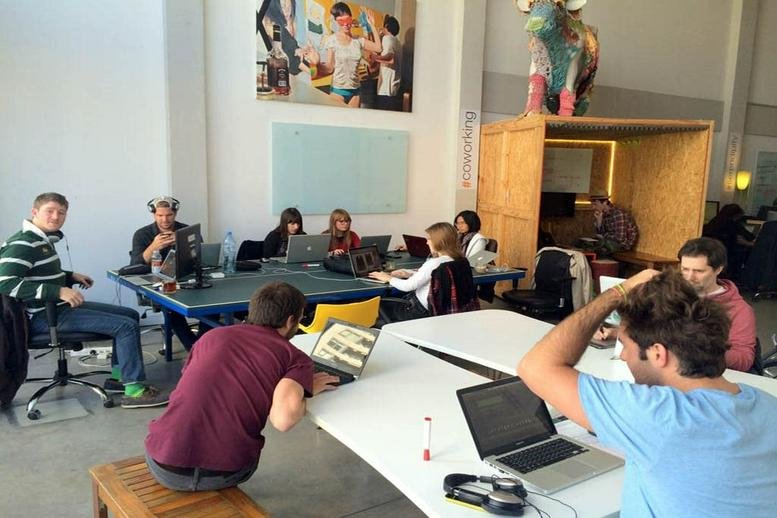 Spacious coworking area at Malabia 1720, 11b, featuring long desks and eclectic decor.