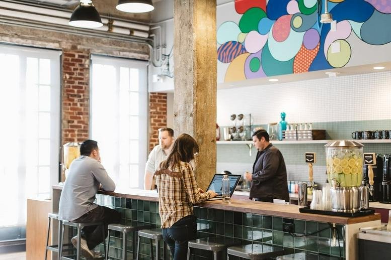 Spacious cafe and breakout area at Mechants Row, 1449 Woodward Avenue with a vibrant wall mural and marble counters.