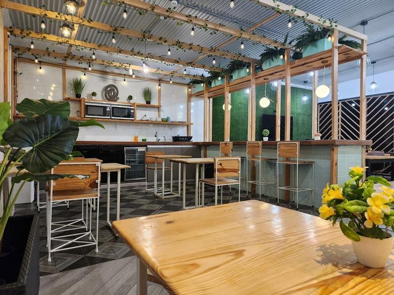 Spacious communal area at Metro Hub Cowork, Ground Floor, Via Espana, Panama City with wooden tables and greenery.