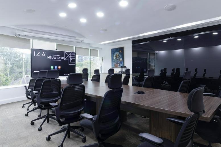 Spacious boardroom at Miravalle, Calzada San Pedro 250, featuring a long wooden table and ergonomic chairs.