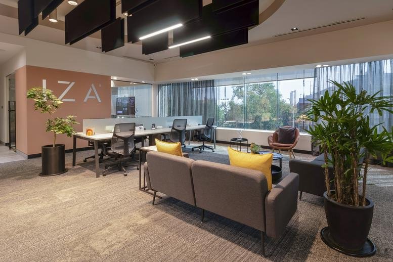Modern workspace at Miravalle, Calzada San Pedro 250, featuring lounge seating, plants, and desk areas.