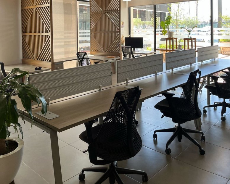 Open-plan coworking area with rows of desks and ergonomic mesh chairs.