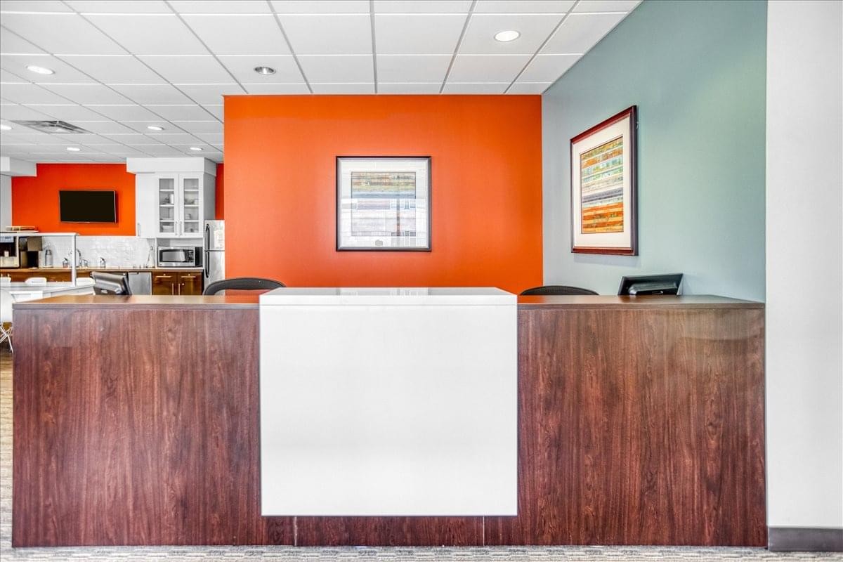 Reception area at North Shore Place II featuring a dark wood desk against a bold orange feature wall.