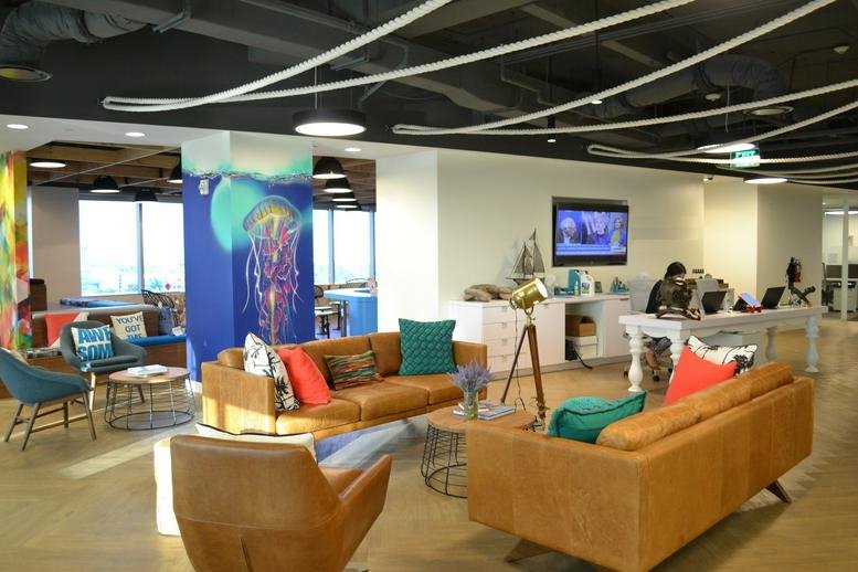Spacious communal lounge at One Financial Plaza, 100 Southeast Third Avenue featuring colorful sofas and a jellyfish mural.