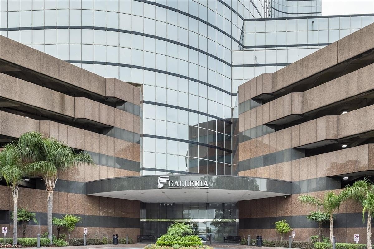 Exterior view of the modern glass facade and covered entrance at One Galleria Boulevard.