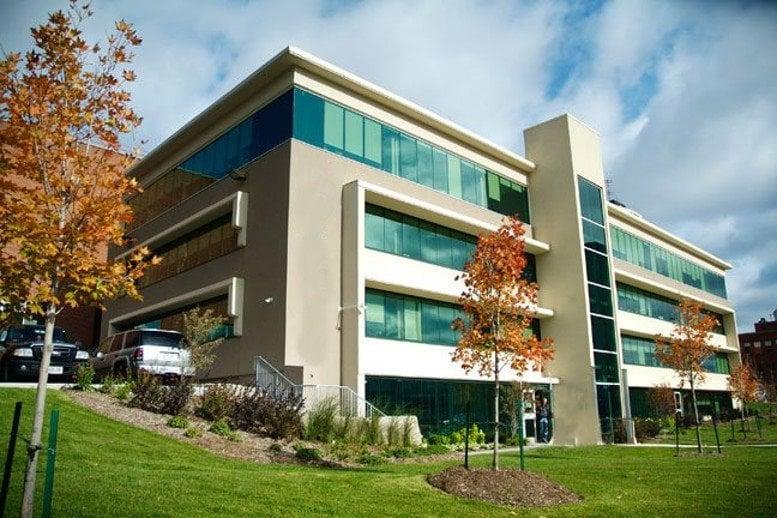 Modern multi-story exterior of One Hunter Street East with glass windows and autumn trees.