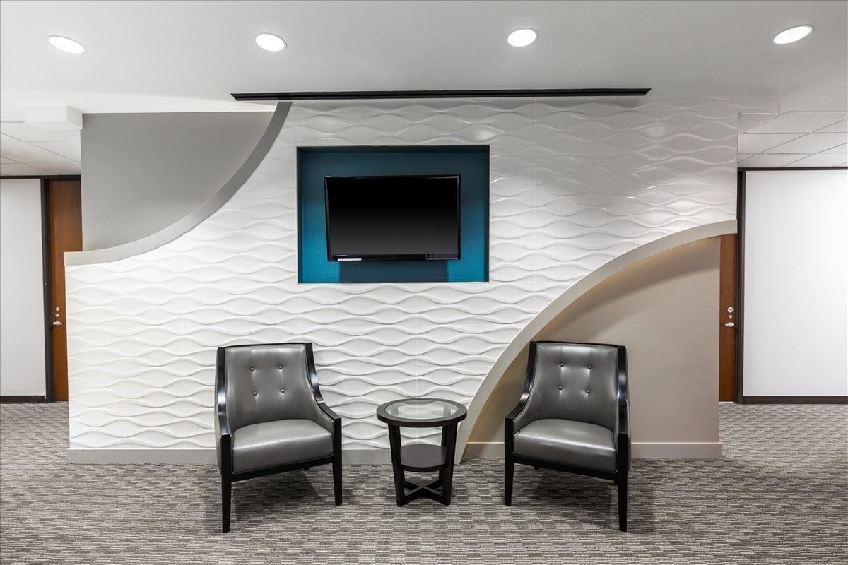 Modern lounge area at One Riverway with wave-patterned feature walls, a blue recessed TV nook, and stylish armchairs.