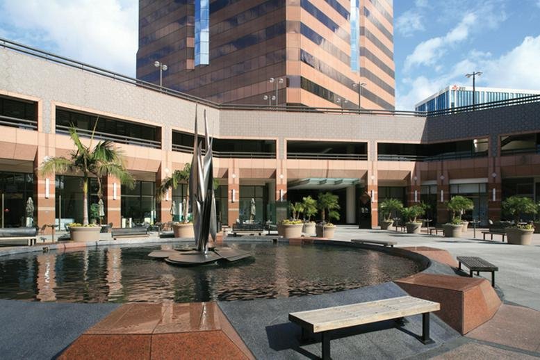 Outdoor plaza courtyard with a central fountain and palm trees in front of the building.