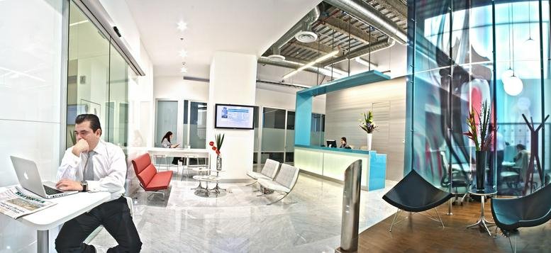 Spacious reception area with a modern desk, seating lounge, and glass partitions.