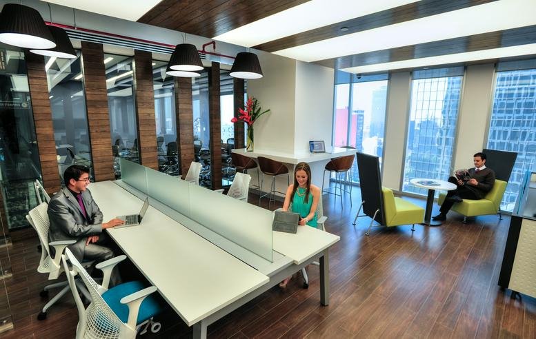 Vibrant communal coworking space with wood flooring, colorful chairs, and city views.