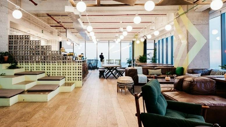 Spacious communal lounge at Paseo de la Reforma 296 with tiered wooden seating, leather sofas, and hanging globe lights.