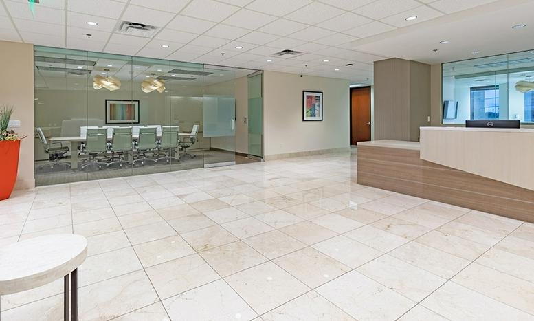 Modern lobby area with glass-walled conference room and warm wood accents.