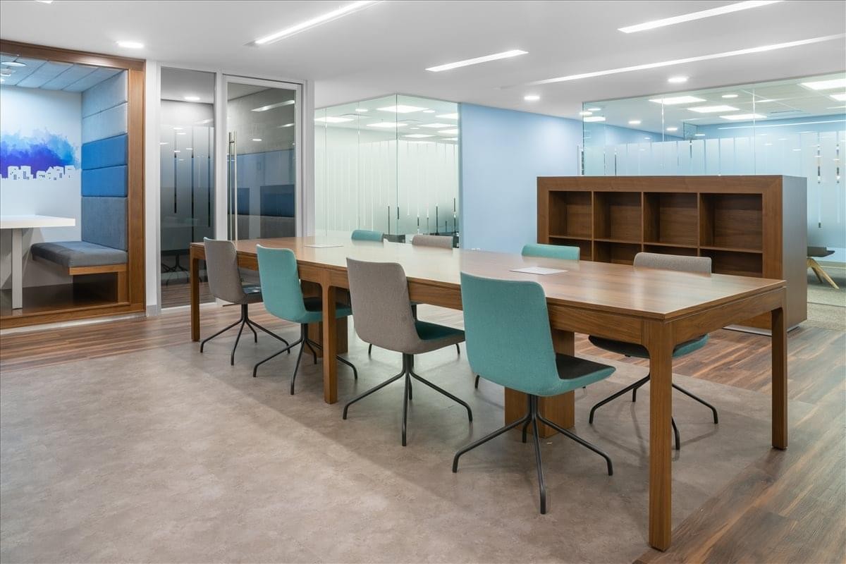 Open-plan workspace at 111 Av. Presidente Masaryk featuring a large wooden table and colorful chairs.