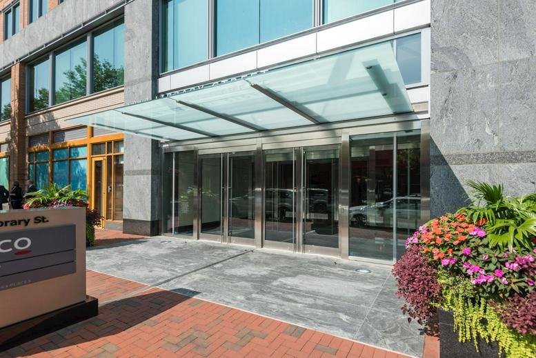 Exterior entrance with glass canopy and colorful flower planters at Reston Town Center, 1818 Library Street.