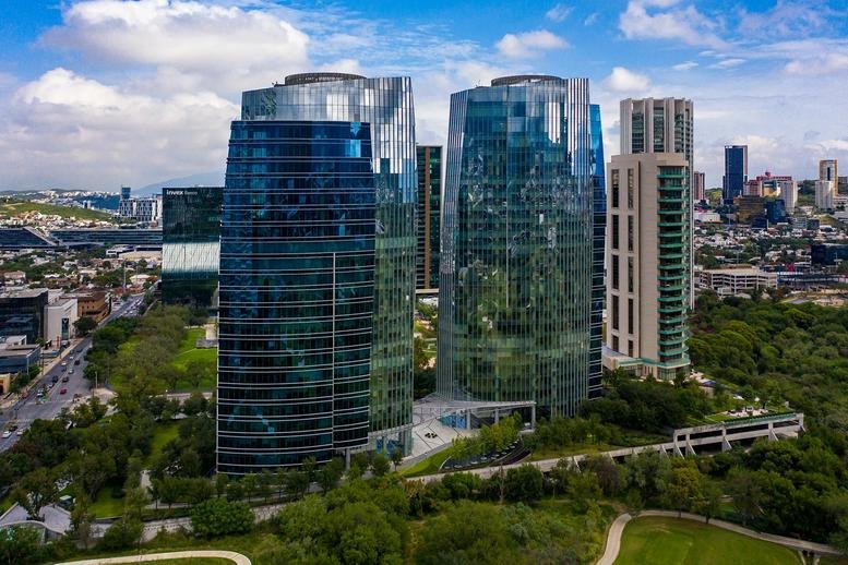 Exterior view of the glass-facade Ricardo Margáin 335 building surrounded by greenery.