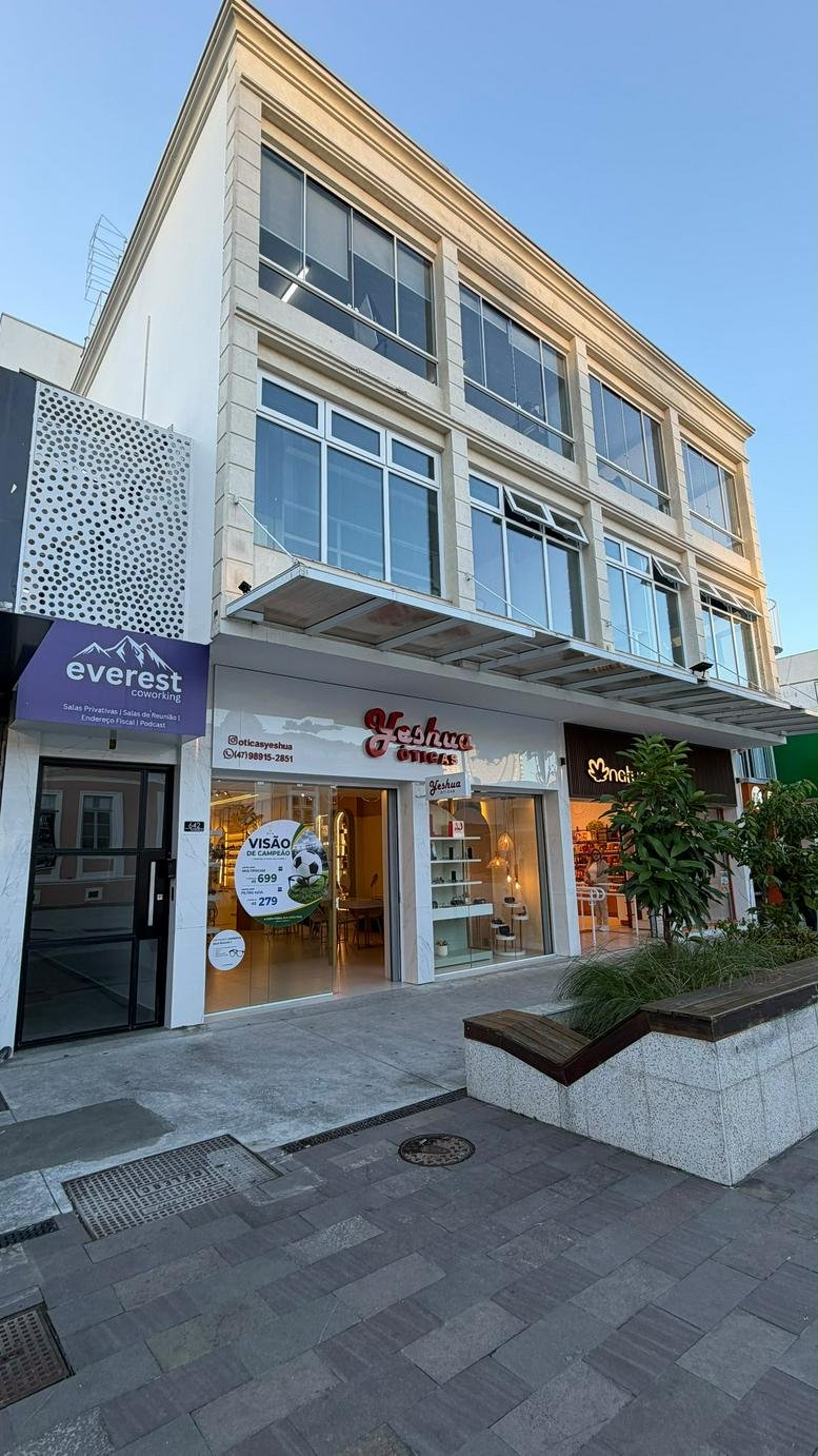 Exterior facade of the Everest Coworking building with retail storefronts and upper-level glass windows.