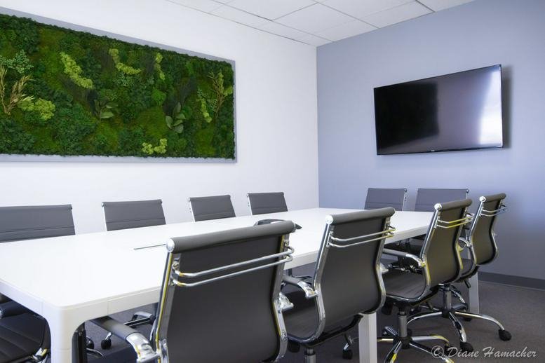 Spacious boardroom with a large white table and a vibrant moss feature wall at Gibbs Drive Coworking Space.