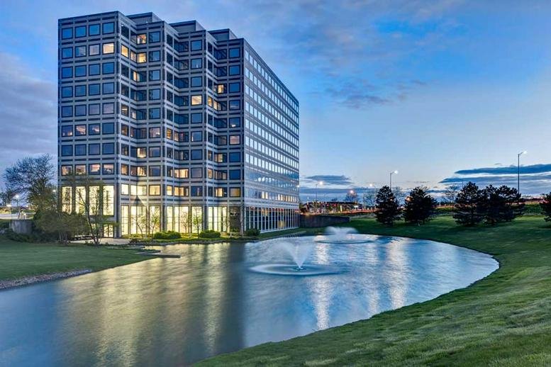 Exterior view of the glass-facade building at 1901 North Roselle Road overlooking a pond with fountains.