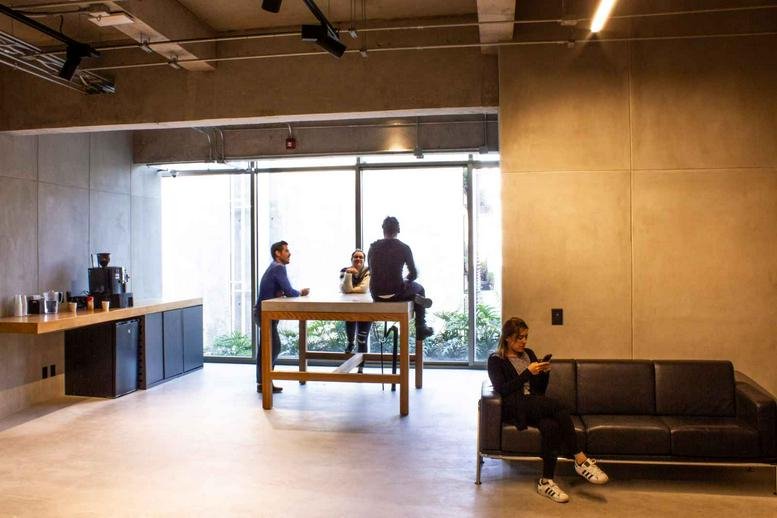 Bright communal lounge with a high table, black sofa, and large windows overlooking greenery.