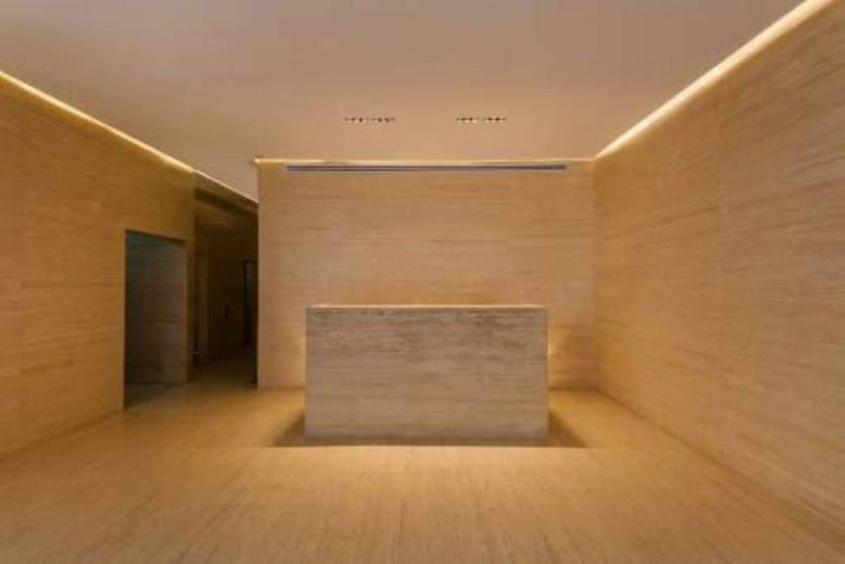 Spacious reception with light wooden panels and a central desk.