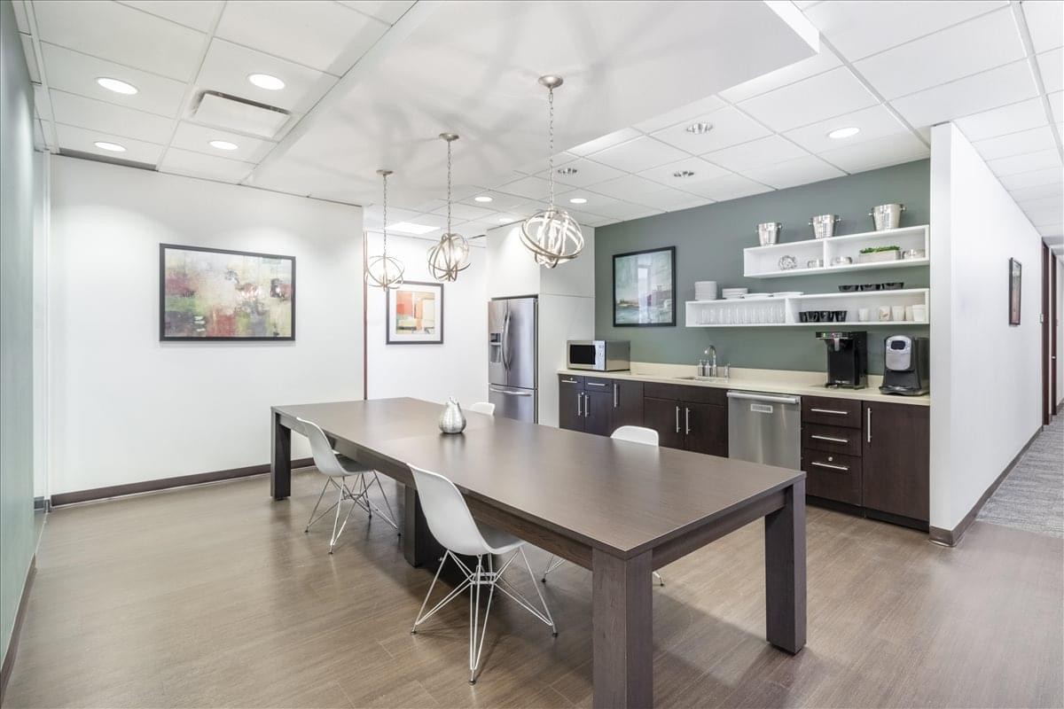 Communal kitchen and dining area at 401 Bay Street, Suite 1600 with a long wooden table and modern pendants.