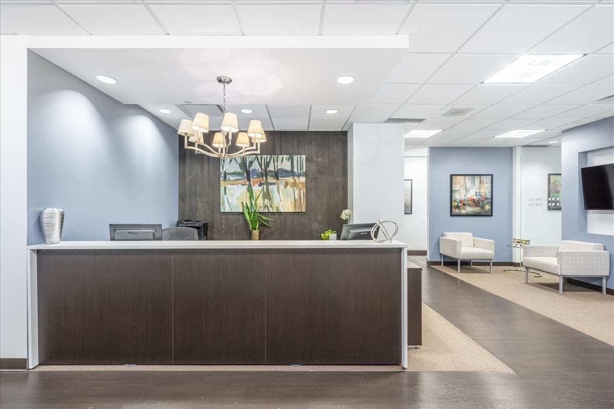 Spacious reception area at 401 Bay Street, Suite 1600, featuring a dark wood desk and chandelier.