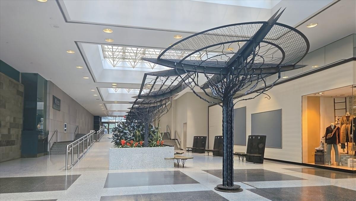 Modern bright atrium lobby at 130 King Street West with a large metal tree-like sculpture.