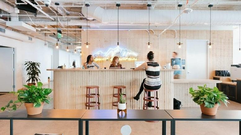 Bright reception area with a wooden front desk and neon mountain art at Tabor Center, 1200 17th Street.