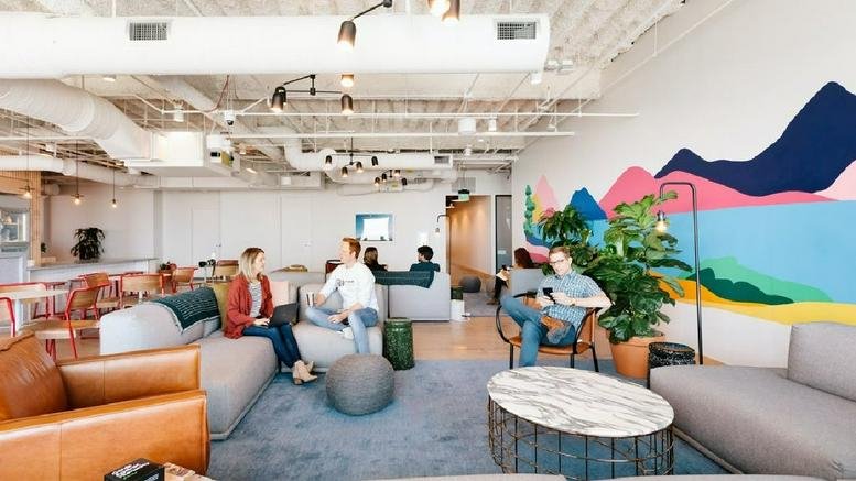 Bright lounge area with a colorful mountain mural, comfortable sofas, and a large plant.