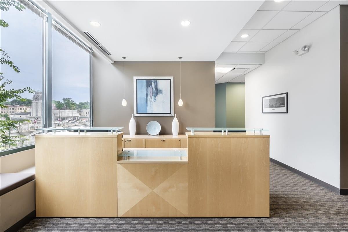 Bright reception area at The Plaza, 100 South First Street, featuring a light wood desk and large windows.