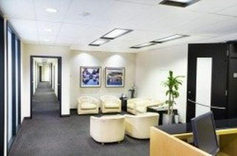 Bright reception lobby featuring white armchairs and a potted plant.