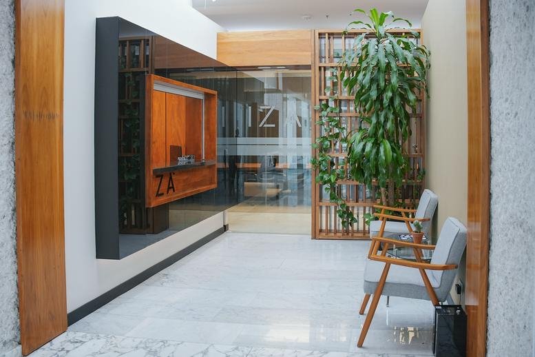 Reception area featuring a wood-panelled front desk and a tall indoor plant.