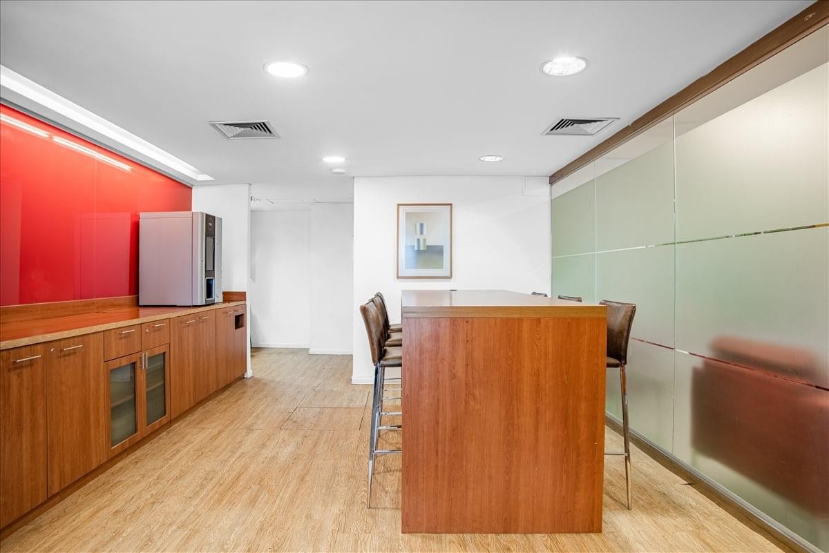 Breakout area with a high wooden table, bar stools, and a vibrant red accent wall.