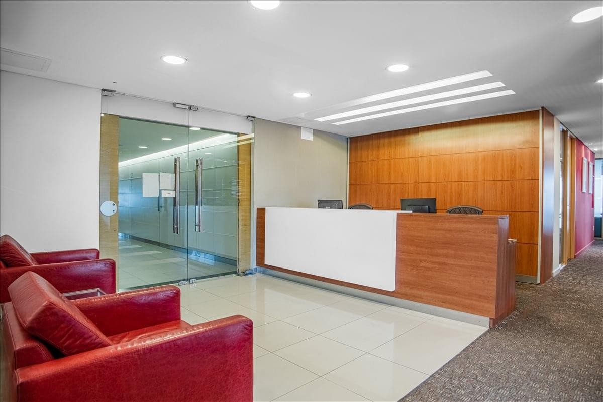 Reception area featuring a wood-fronted desk and vibrant red leather chairs.