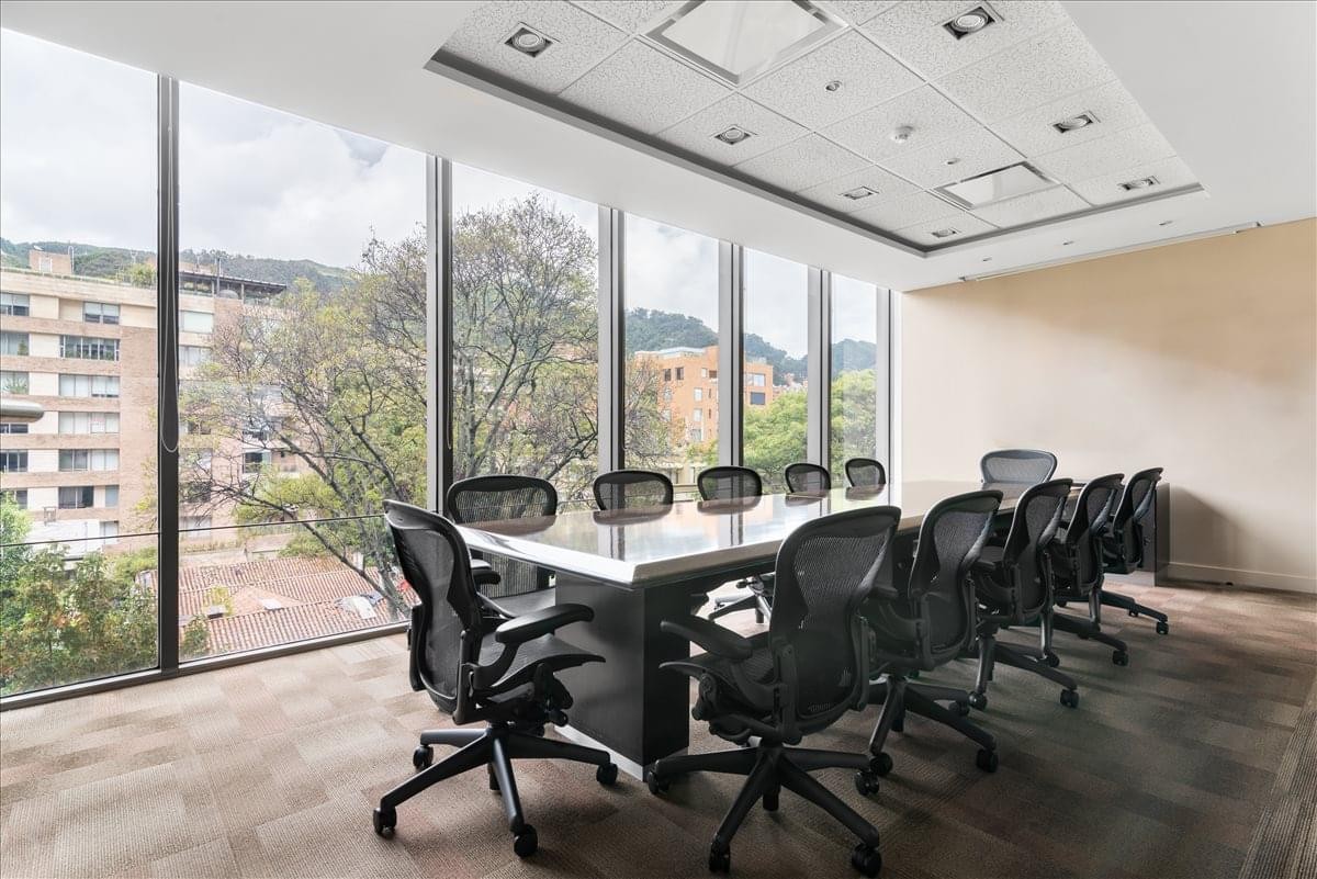 Professional meeting room at the Urban Plaza Building featuring a long table and black mesh chairs.